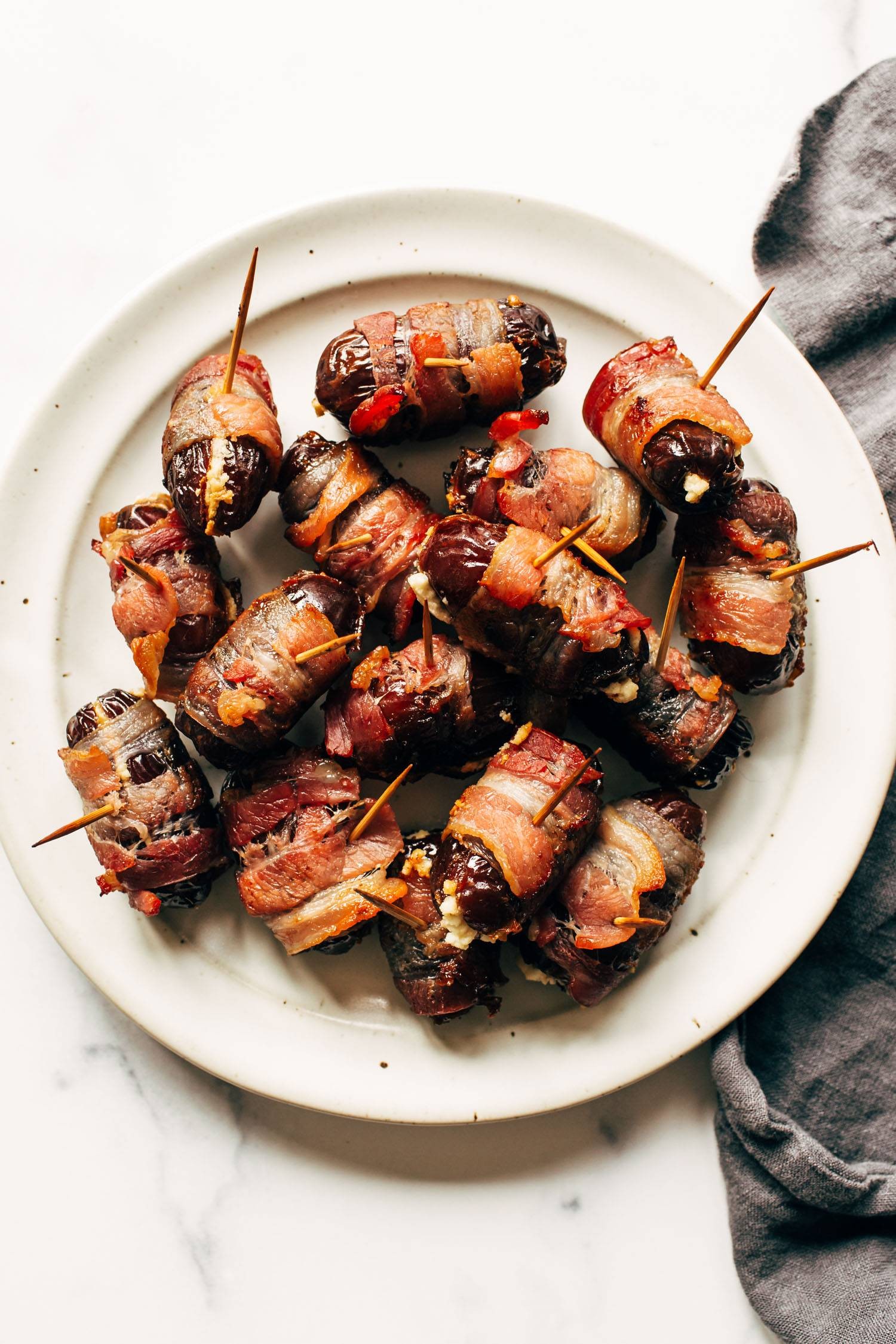 Close-up shot of bacon-wrapped dates stuffed with goat cheese, glistening from the oven