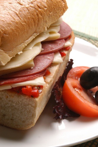 Close-up shot of a spicy Italian panini with provolone, oozing cheese, and visible salami and roasted red peppers.