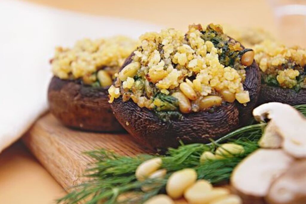 basil and pine nut stuffed mushrooms on a rustic wooden board