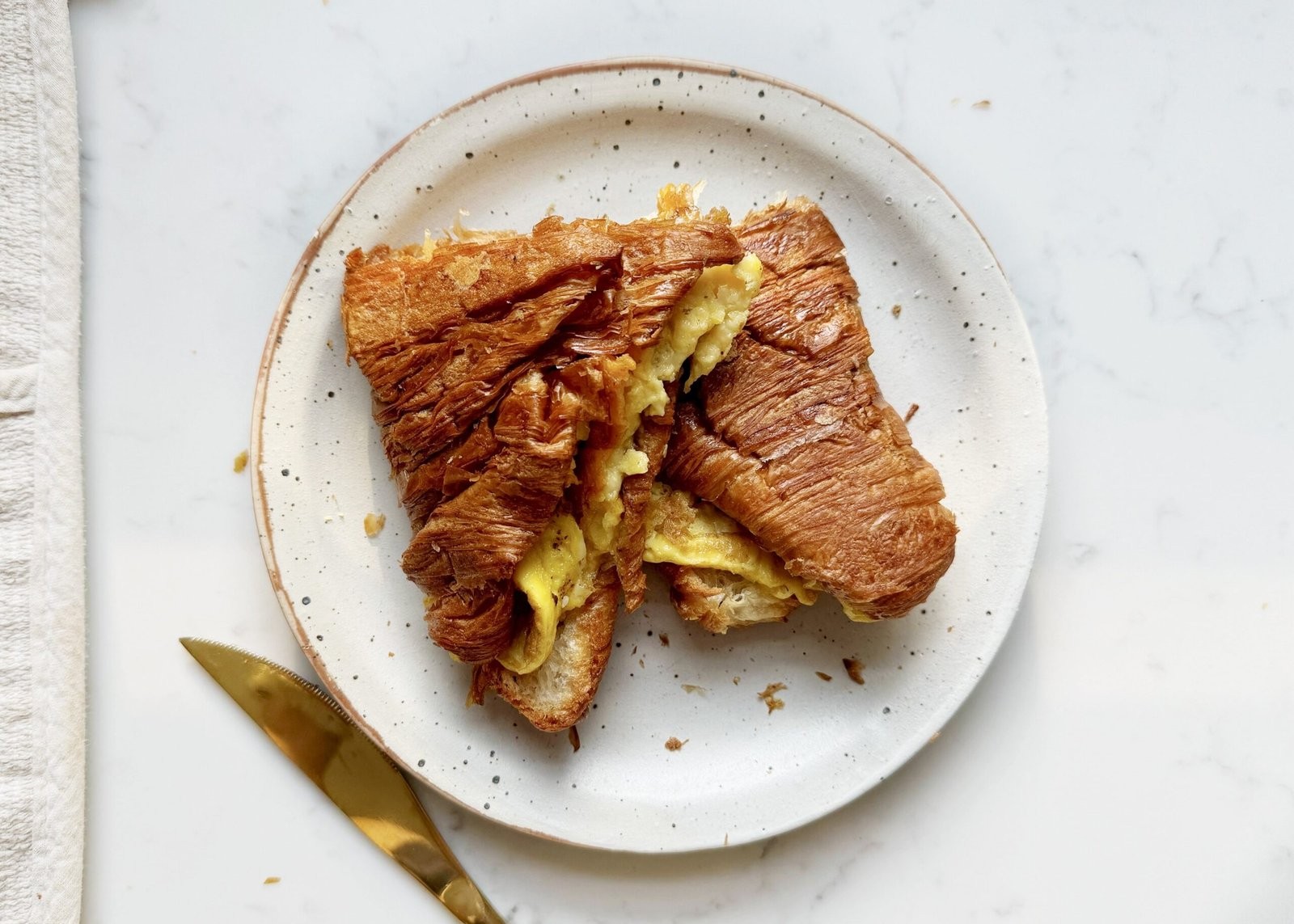 Close-up of a golden brown breakfast cheddar egg melt on a plate, with steam rising.