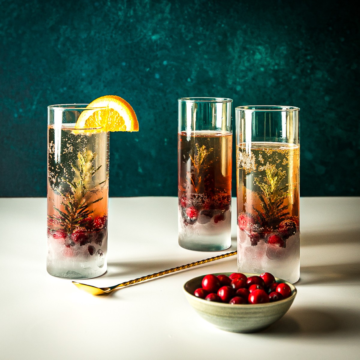 elegant non-alcoholic sparkling holiday drink in a flute glass with cranberries and a rosemary sprig