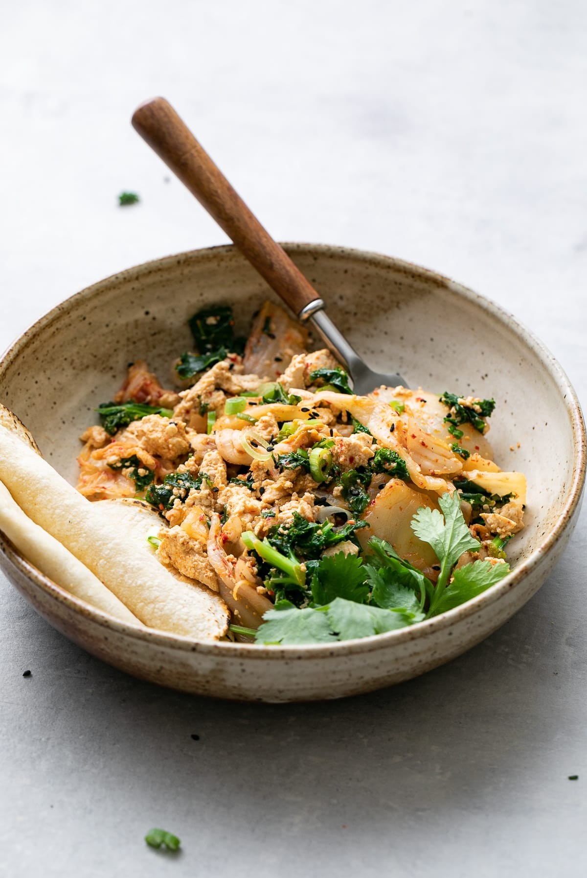 Sautéed tofu scramble with kimchi and sesame oil in a skillet