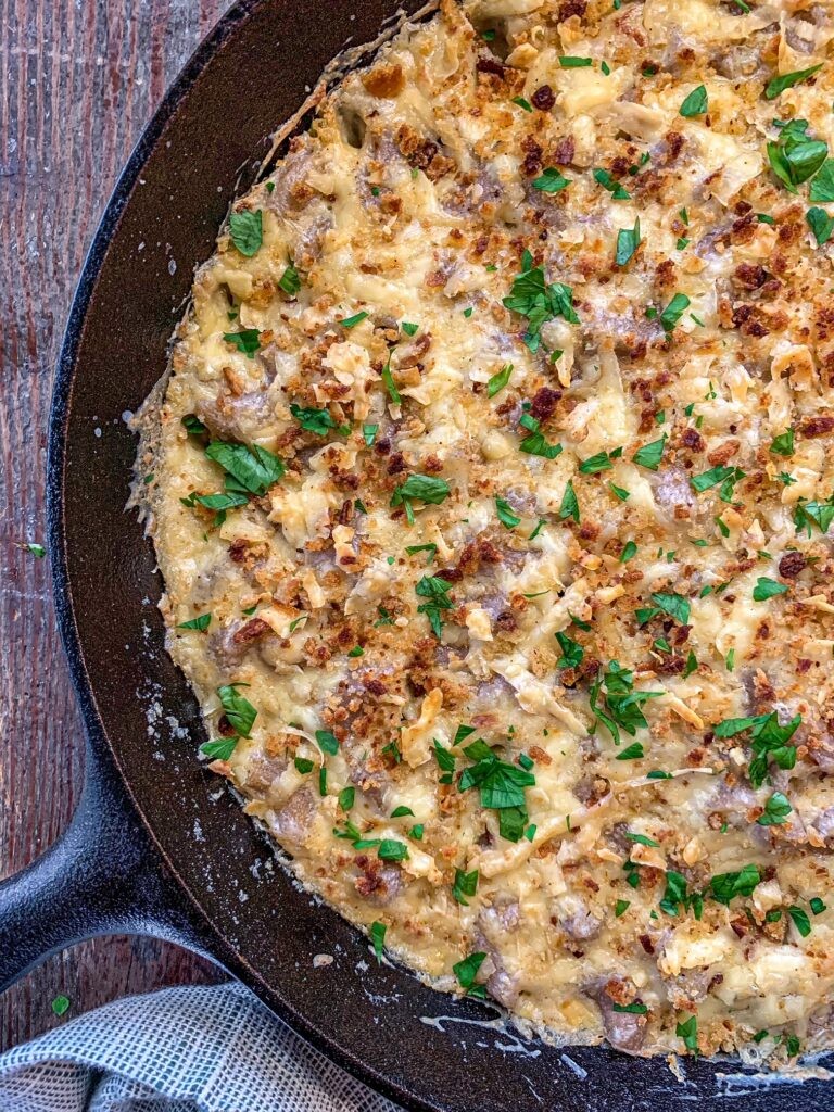 overhead shot of creamy, golden extra-velvet mac and cheese in a cast iron skillet with fresh parsley garnish