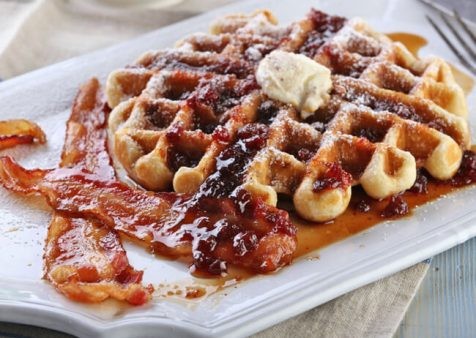 stack of lingonberry-maple syrup waffles topped with fresh lingonberries and a drizzle of syrup