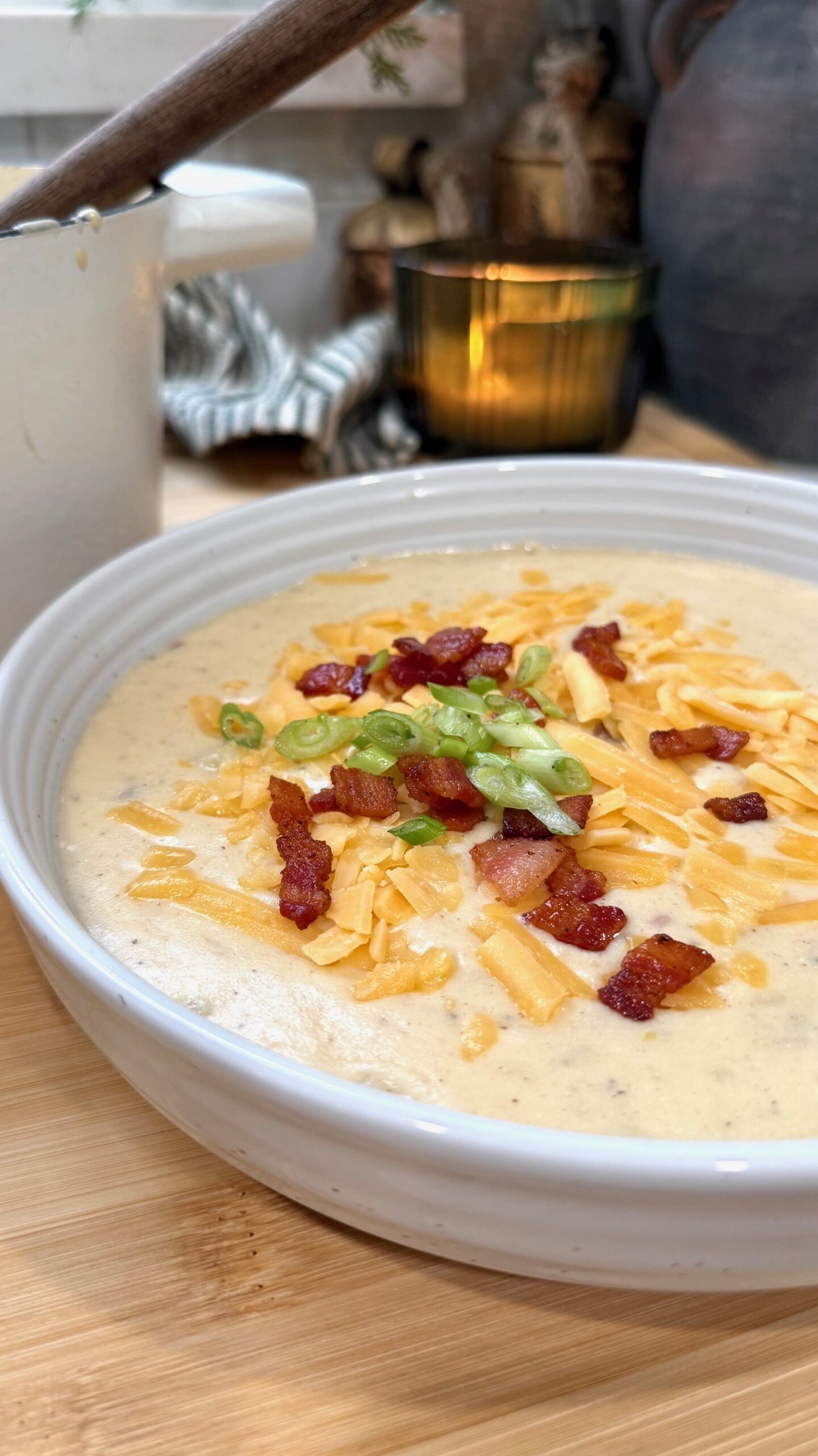 Cozy bowl of creamy potato soup with bacon and green onions, rustic wooden table, steaming hot.