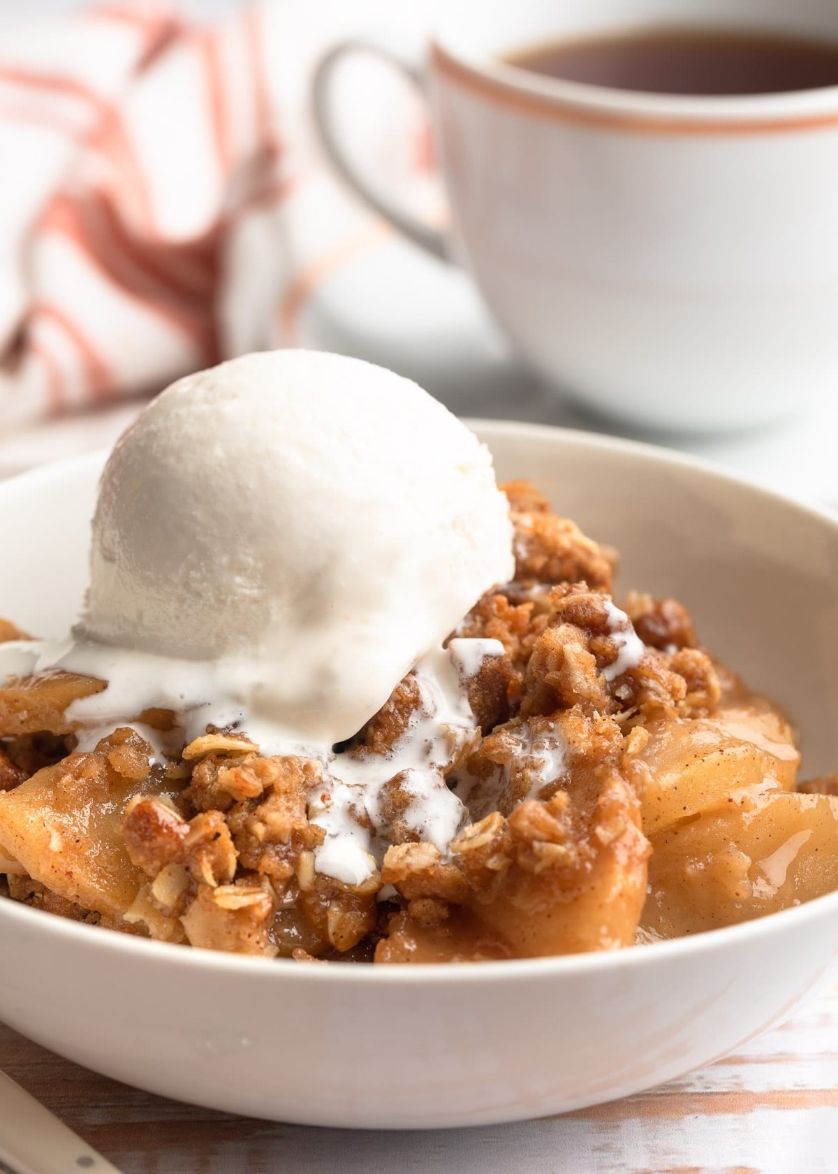 Rustic caramel apple crisp, bubbling, with a scoop of vanilla ice cream, cozy Thanksgiving setting
