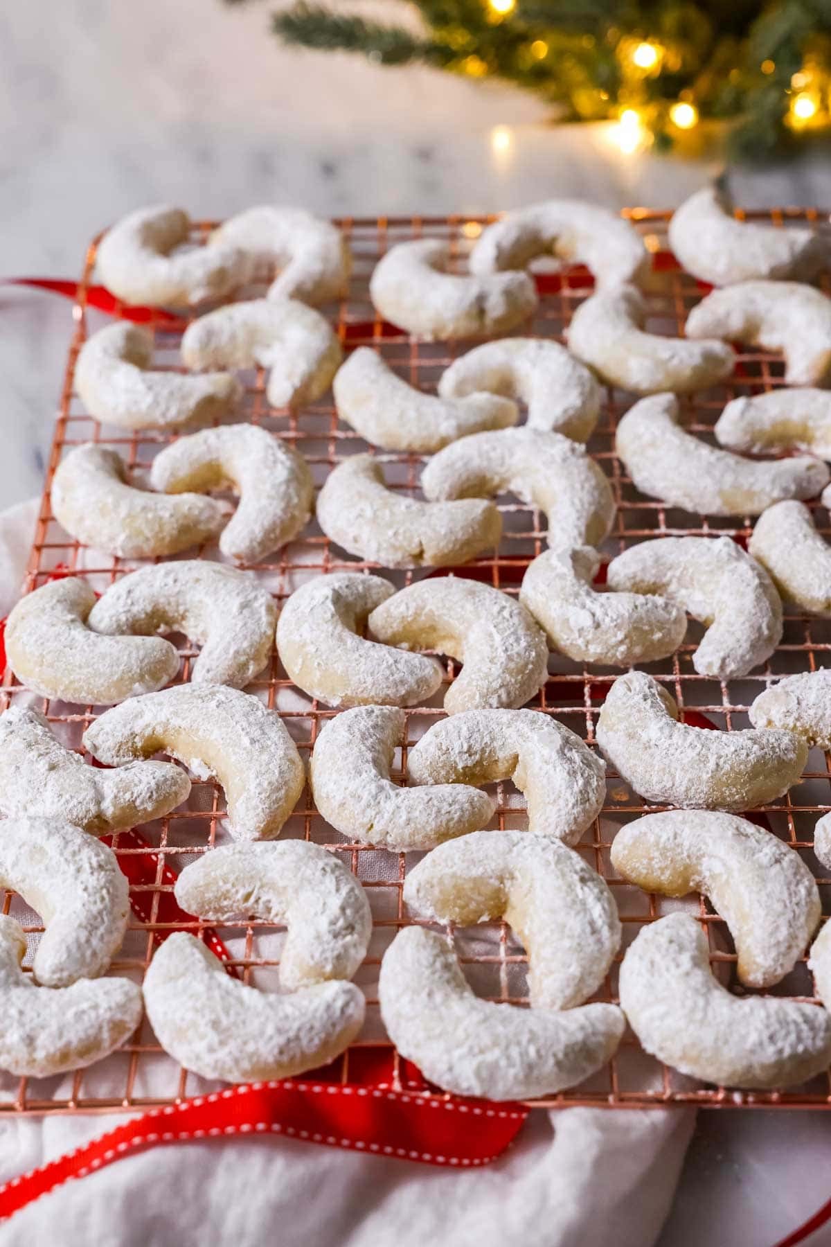 freshly baked almond crescent cookies dusted with powdered sugar on a cooling rack, cozy kitchen setting