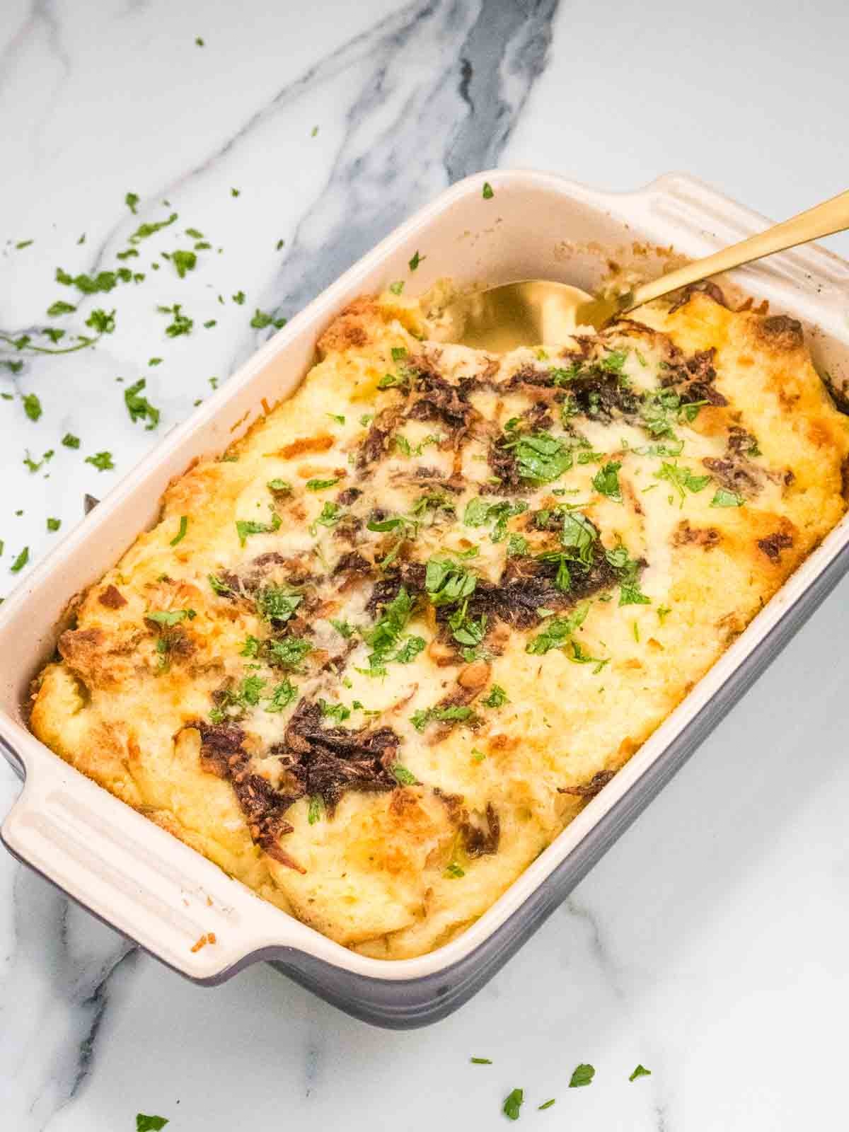 Close-up shot of Chili Cheese Fries Stale Bread Pudding, showing the cheesy, chili-laden bread pudding in a baking dish
