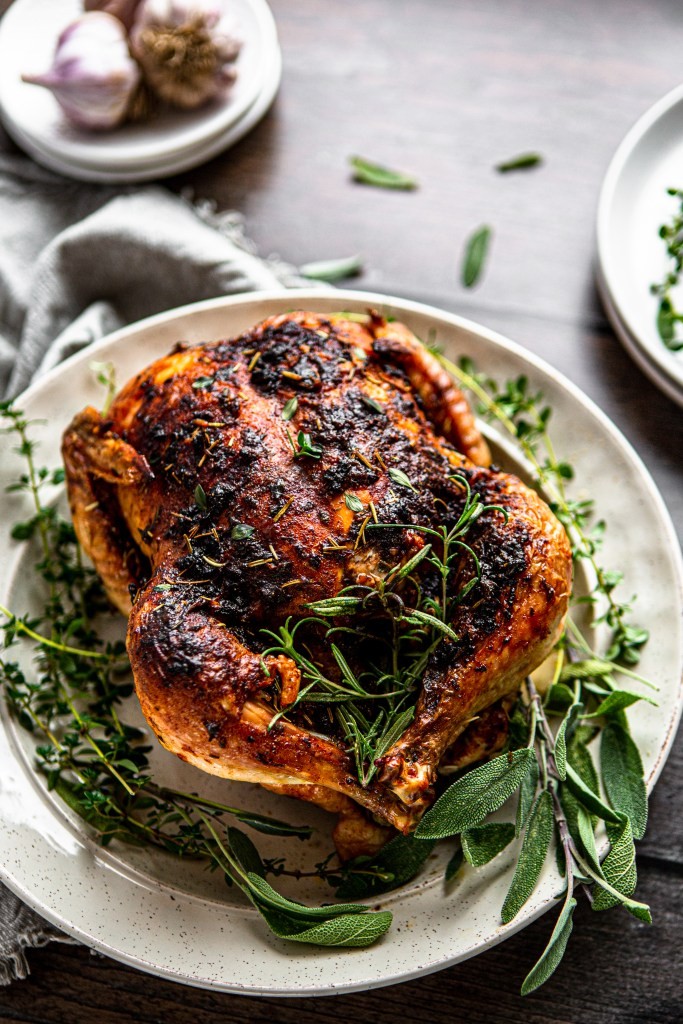 A juicy roasted chicken with thyme and oregano sprigs