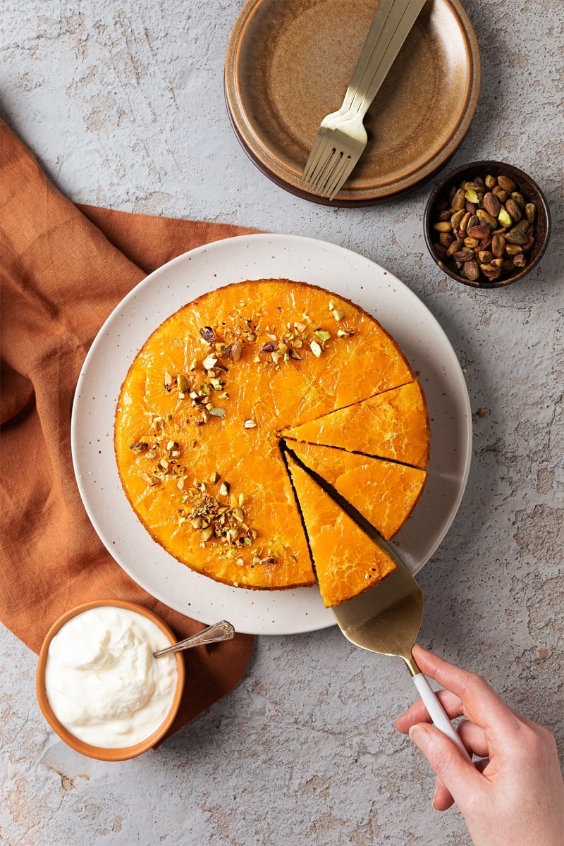 overhead shot of a slice of orange and almond polenta cake with a cup of coffee