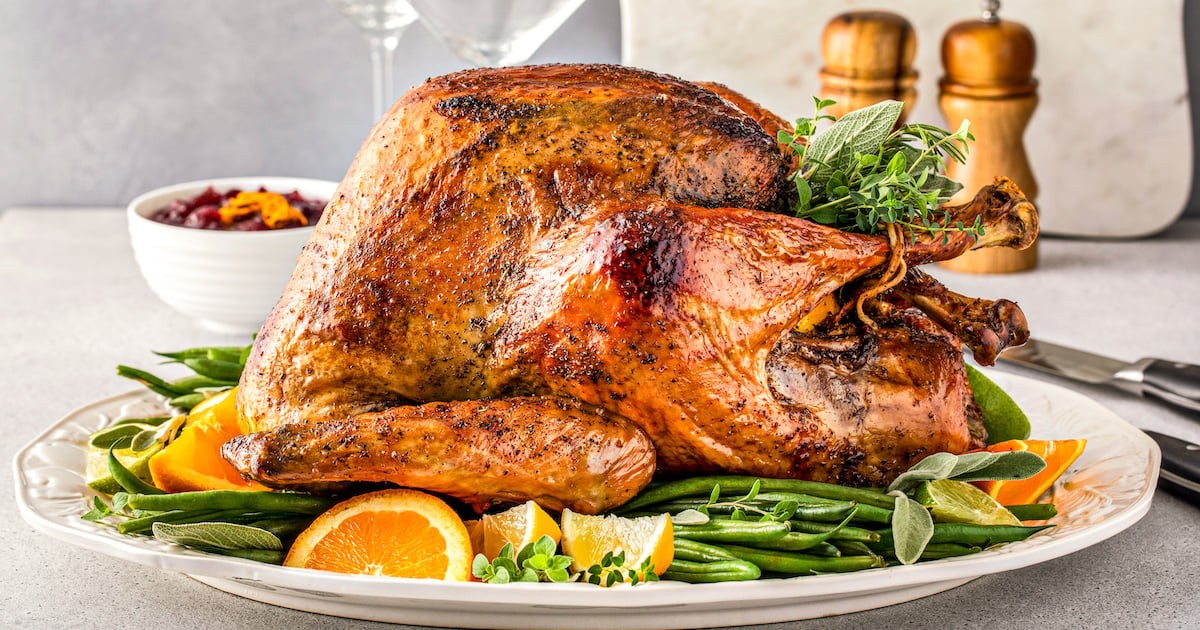 golden brown whole roasted turkey with garlic and thyme on a platter, festive table setting