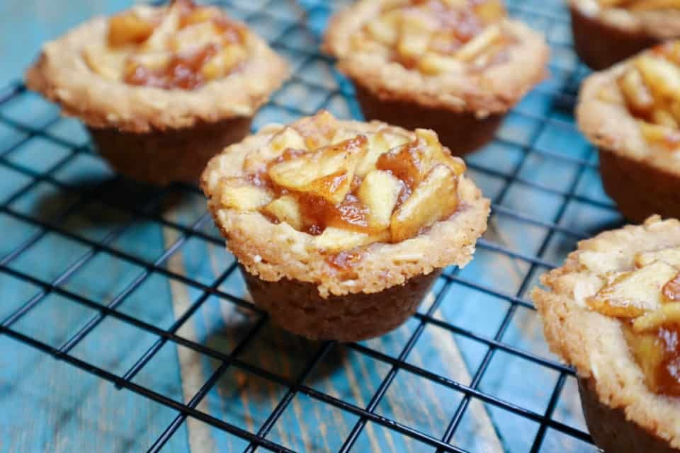 Close-up shot of golden-brown apple crisp crumble cups in a muffin tin