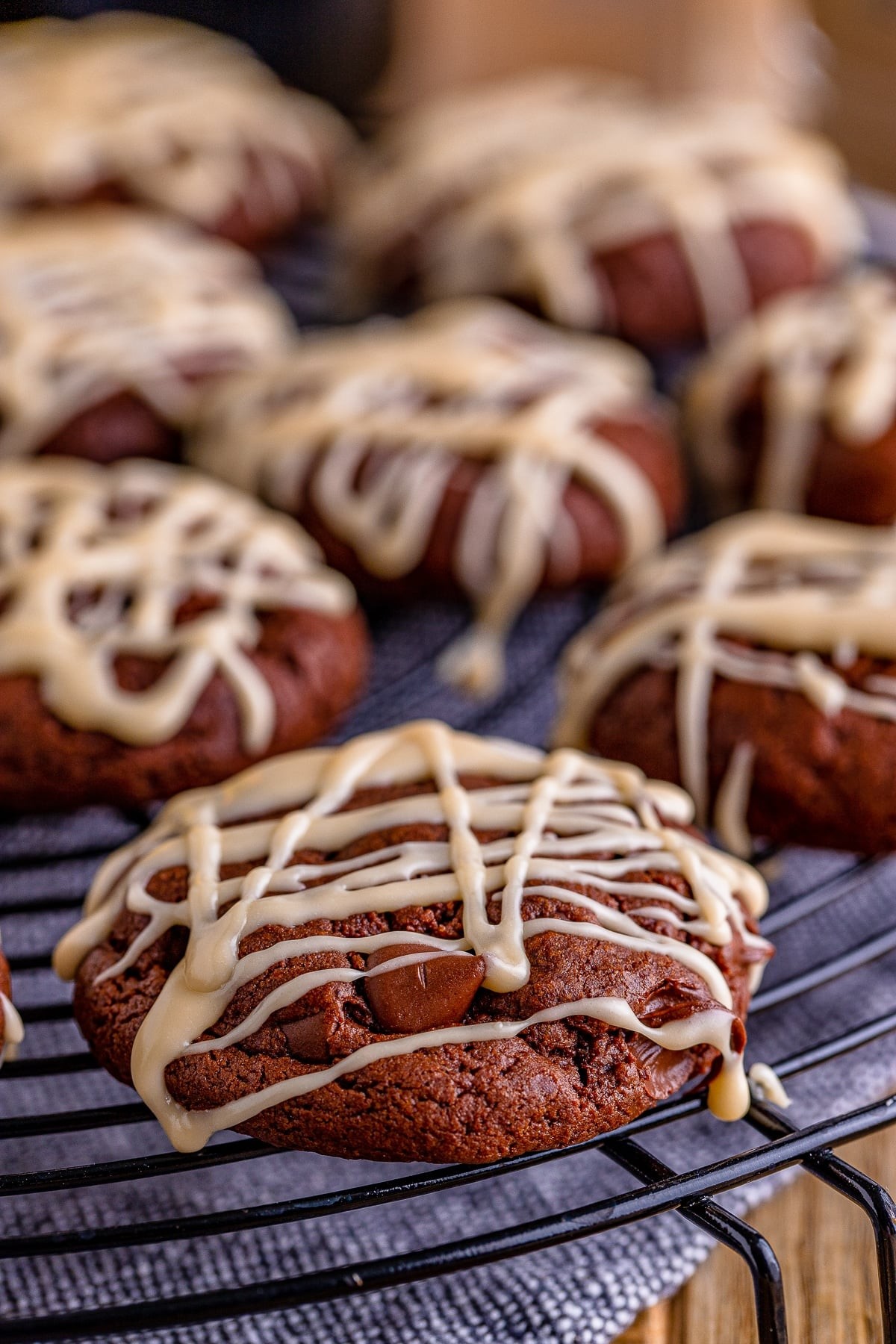 Close-up of freshly baked cocoa cookies with white chocolate drizzle on a cooling rack