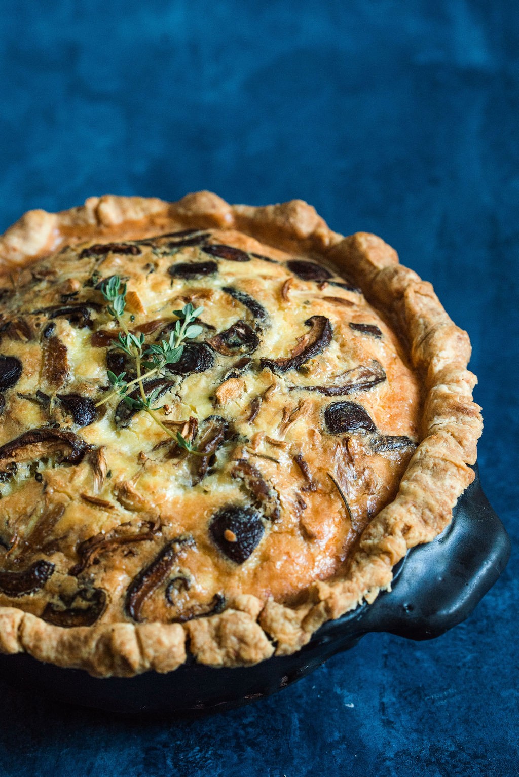 wild mushroom and provolone quiche with thyme on a rustic wooden table