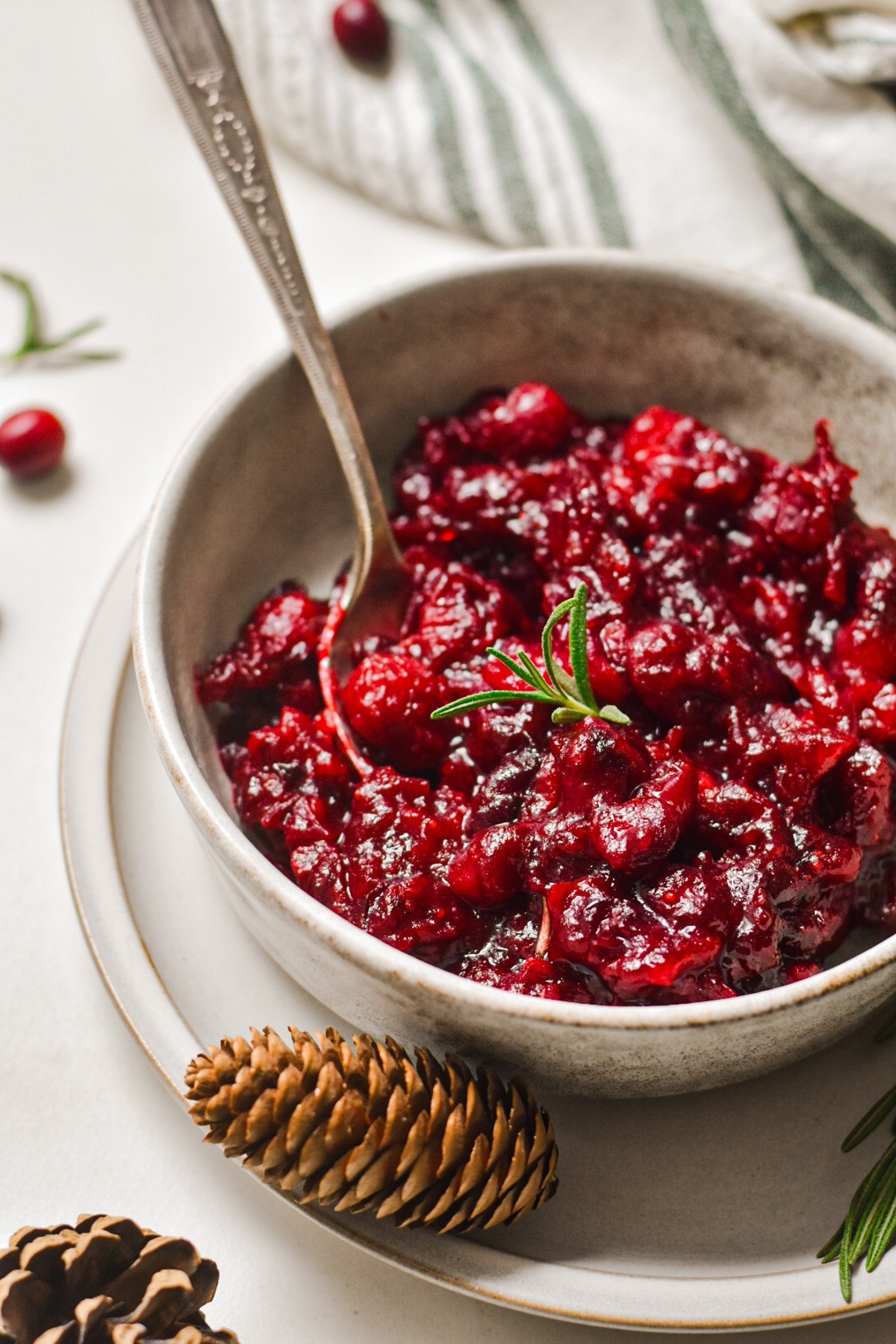 Vibrant cranberry sauce with fresh ginger, served in a rustic bowl with holiday decor