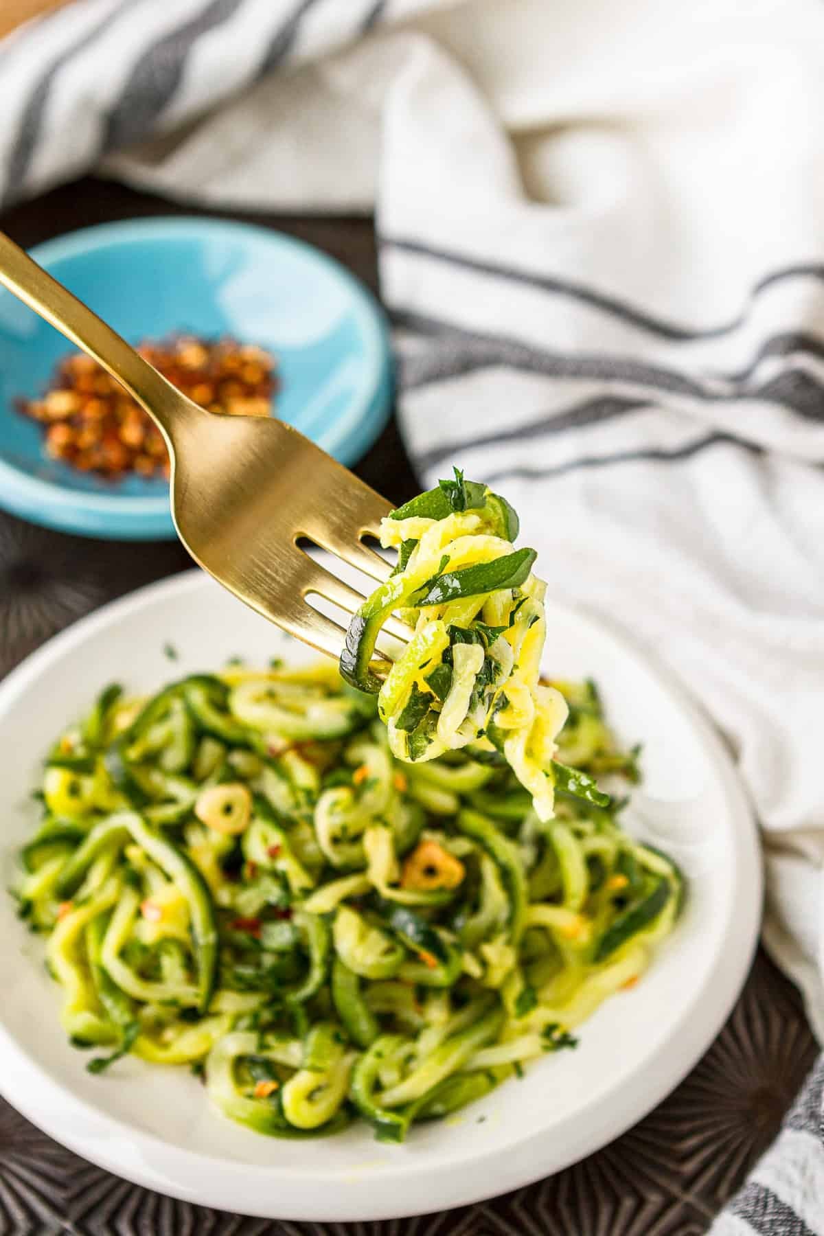 vibrant plate of zucchini noodles with sautéed garlic, olive oil, and fresh parsley, brightly lit, close-up