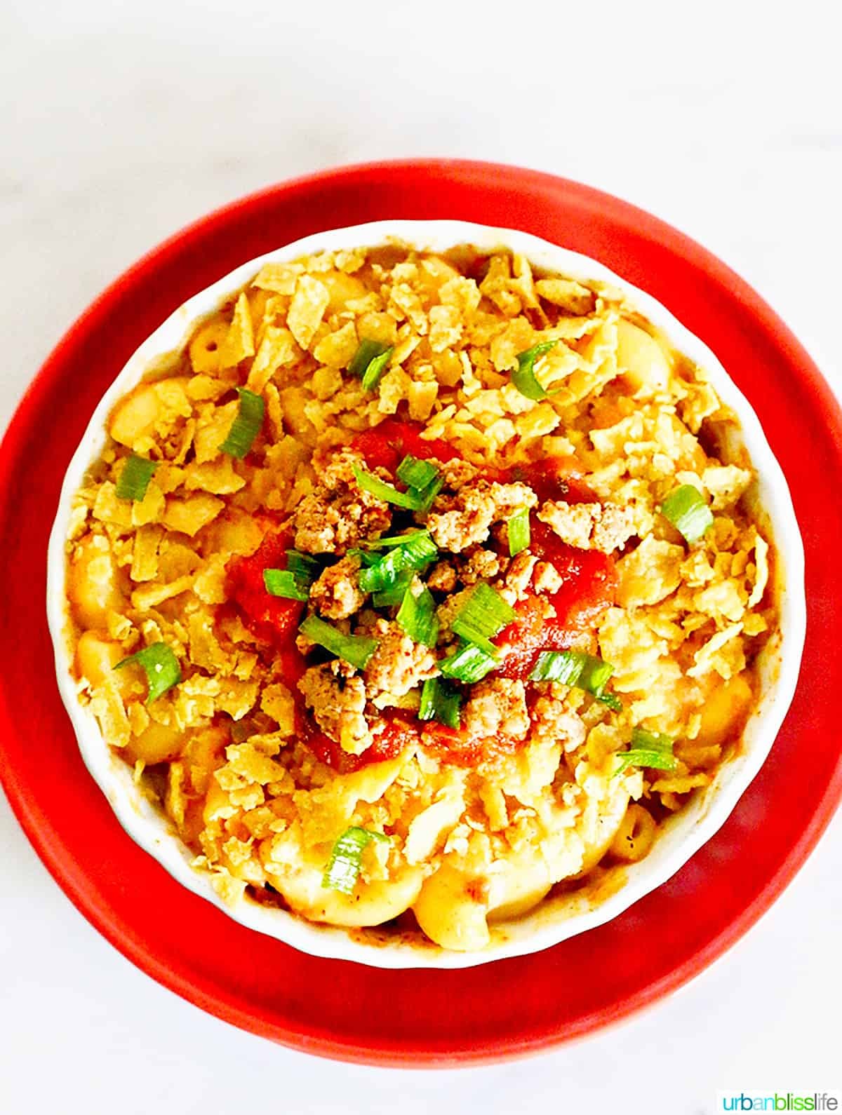 A golden-brown 9x13 inch baking dish filled with Taco Mac and Cheese, garnished with fresh cilantro and diced tomatoes.