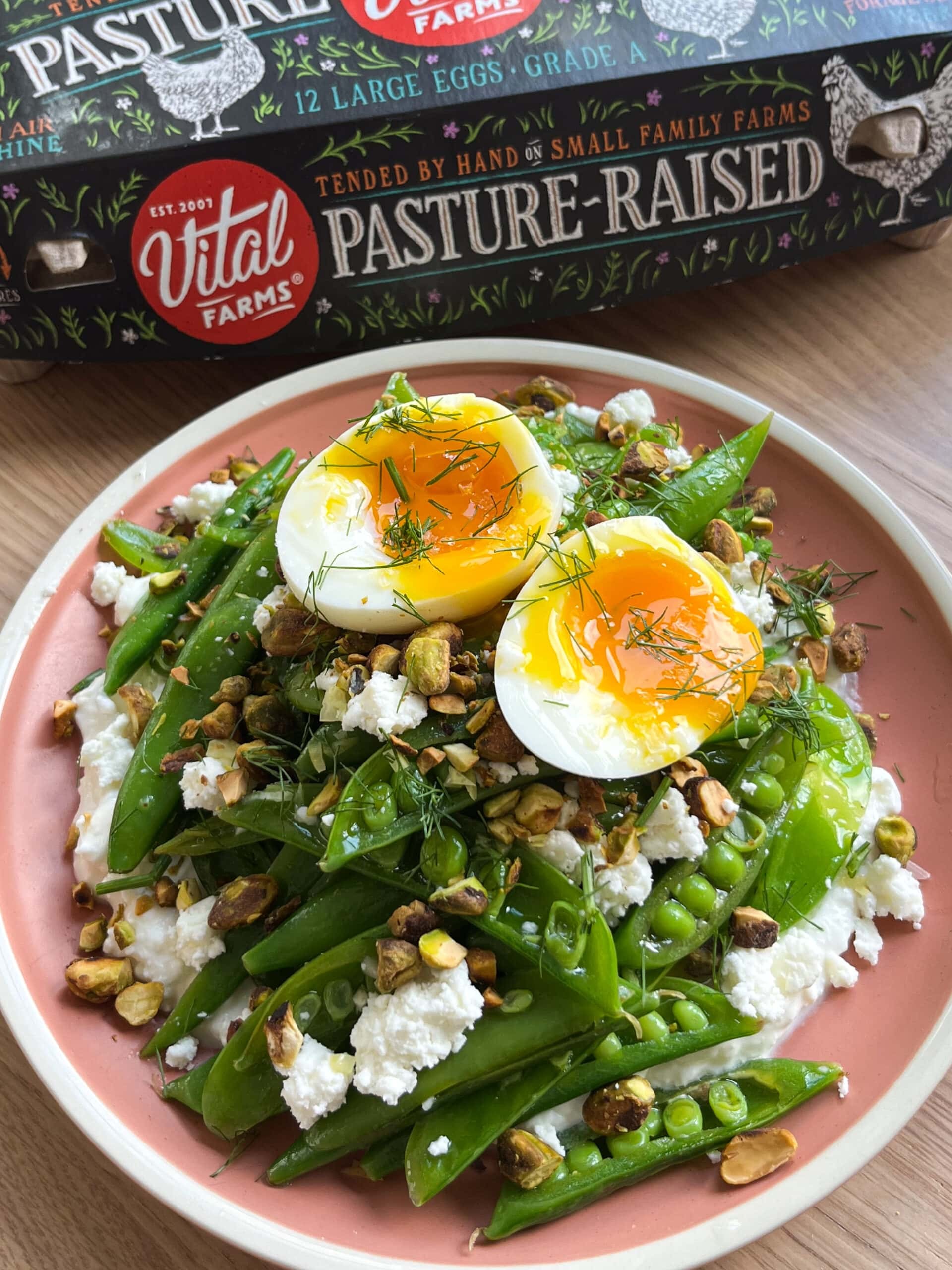 Sautéed eggs with sugar snap peas and lemon zest on a white plate
