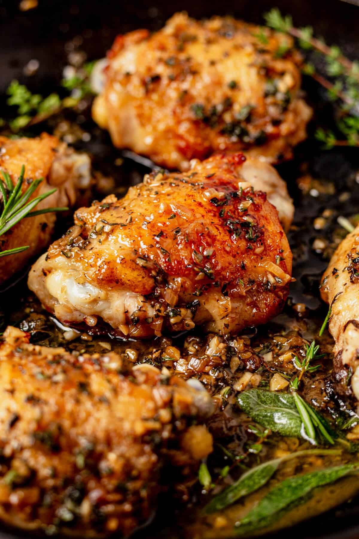 Golden brown crispy chicken thighs in a cast iron skillet with herbs