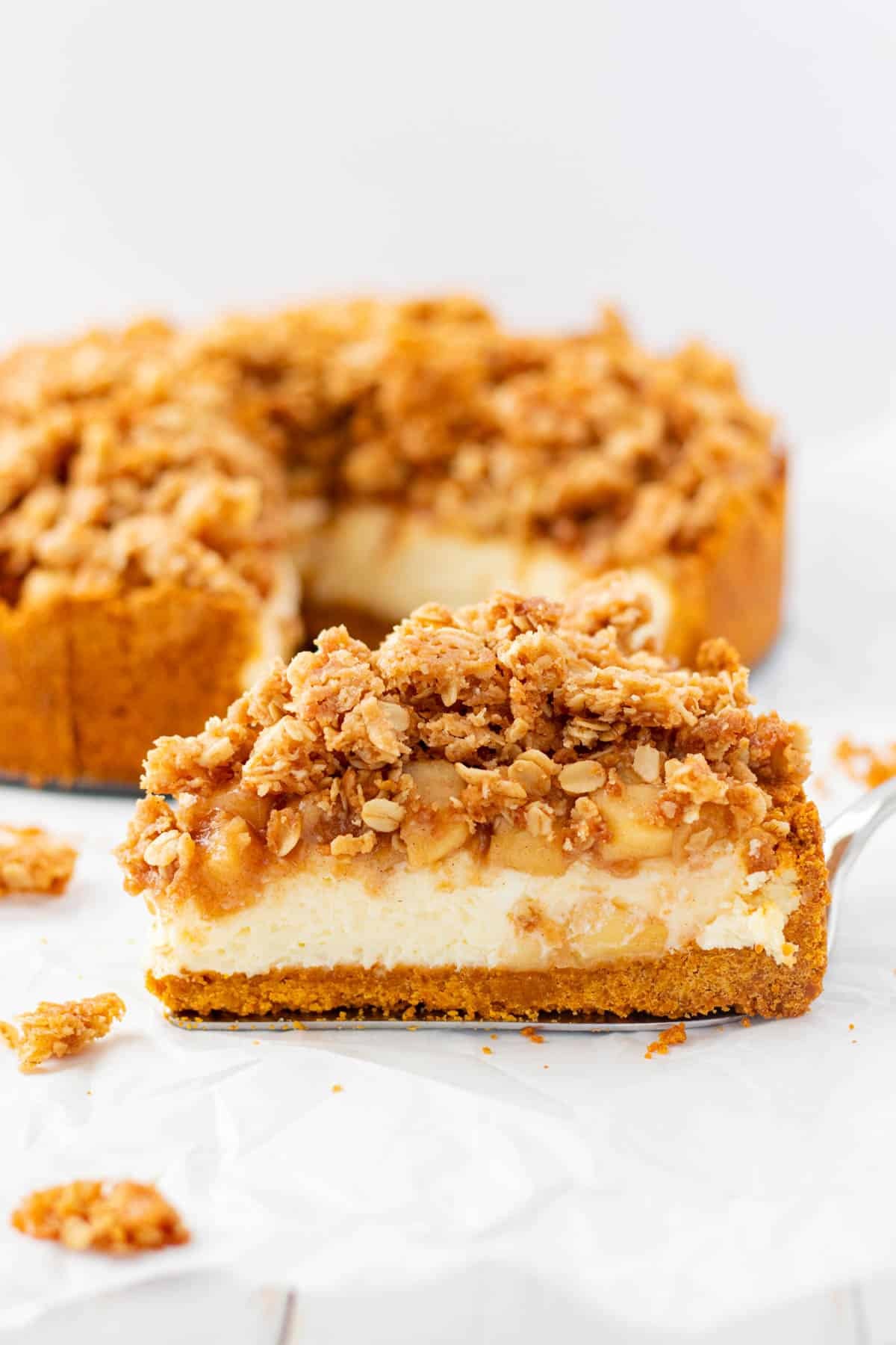 overhead shot of a slice of apple crumble cheesecake with a warm beverage beside it