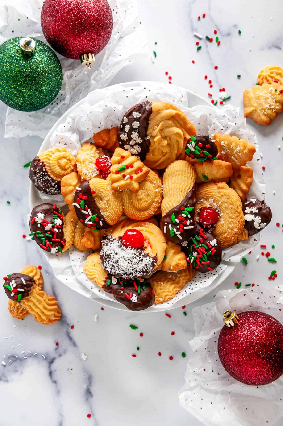 festive platter of beautifully decorated Christmas french tip almond cookies with glossy white icing and sprinkles
