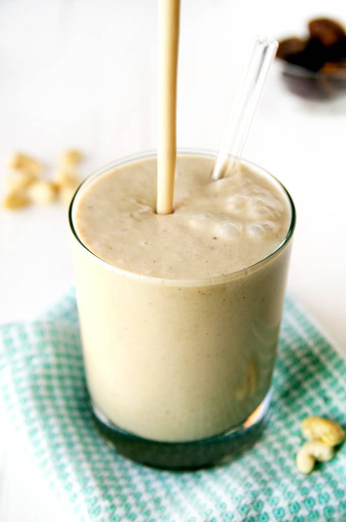 close up of a cashew cream vegan smoothie in a glass with fresh fruit