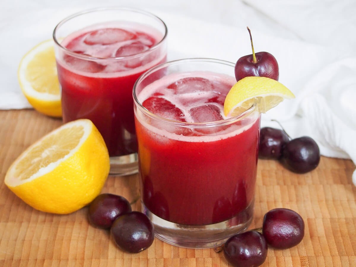 pitcher of cherry almond lemonade with fresh cherries and lemon slices