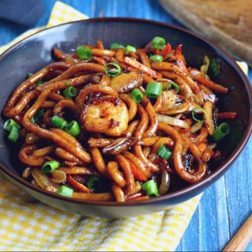 spicy udon noodles with shrimp and colorful vegetables in a bowl