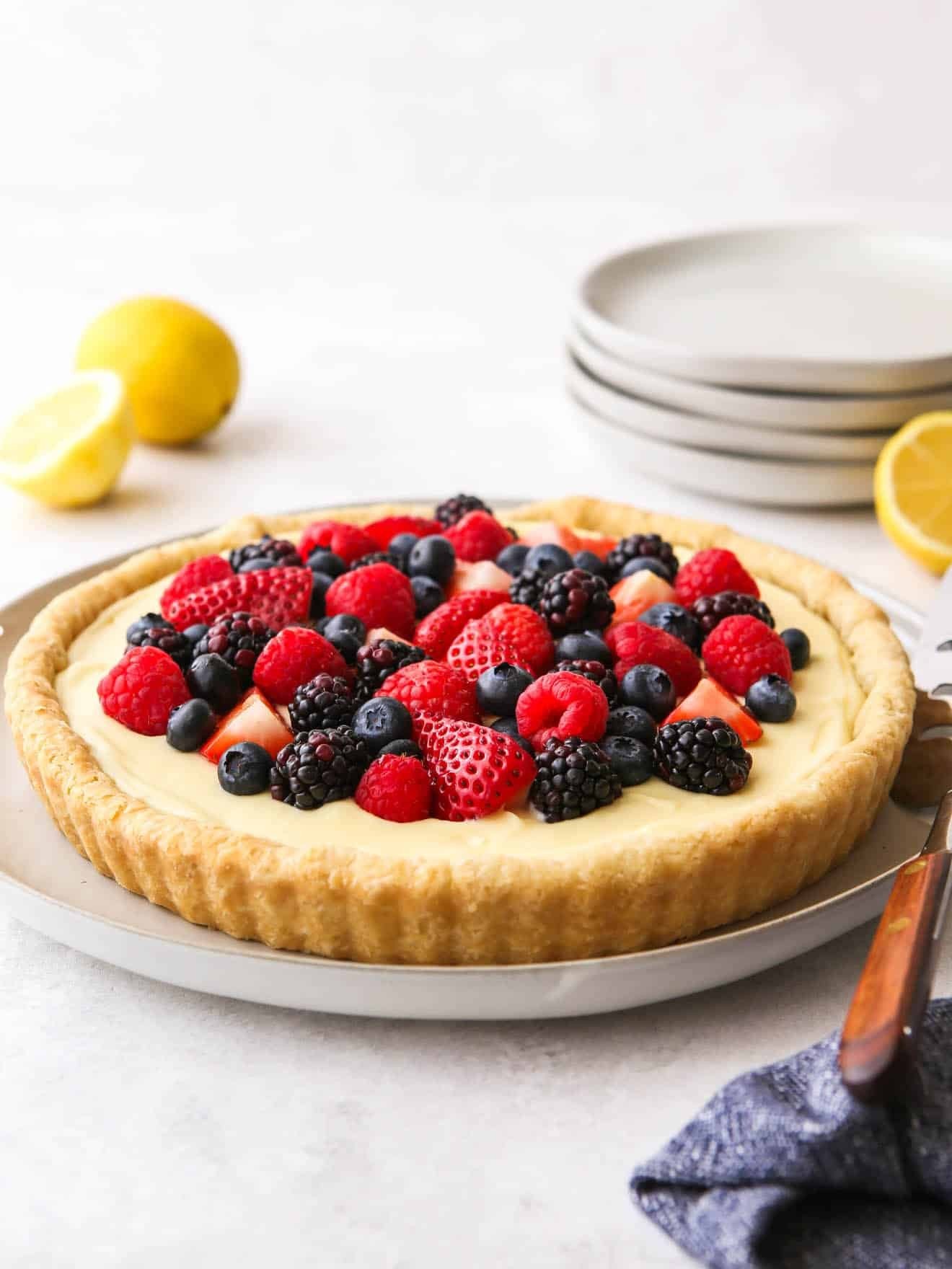 Vibrant lemon custard tart with fresh berries and mint garnish, bright natural light