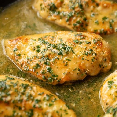 sizzling garlic butter chicken in a skillet, golden brown and garnished with parsley