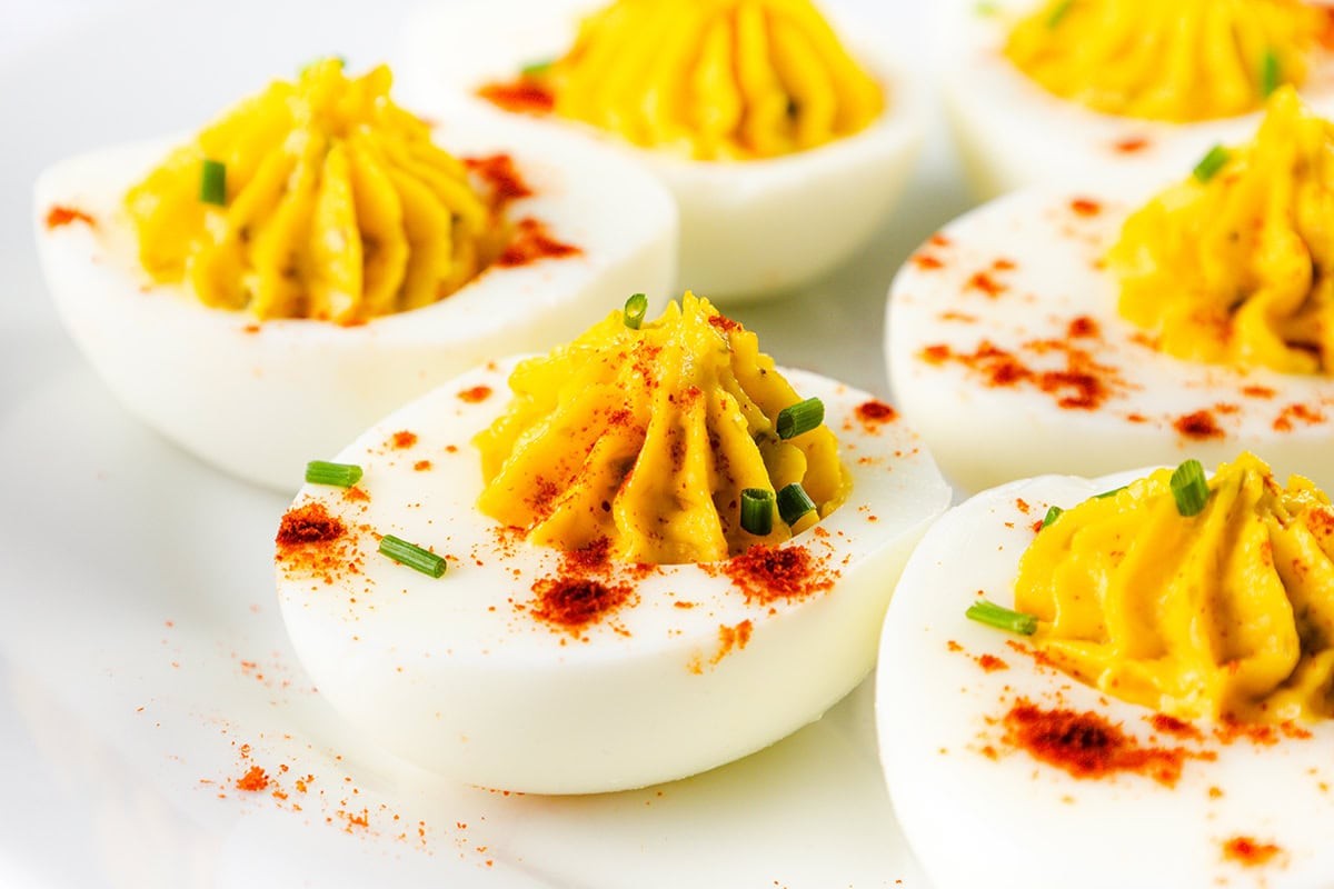 platter of deviled eggs with smoked paprika and fresh chives, close-up, vibrant yellow yolk filling