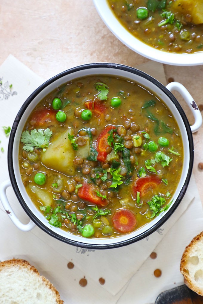 Rustic lentil vegetable stew in a ceramic bowl with crusty bread, steam rising