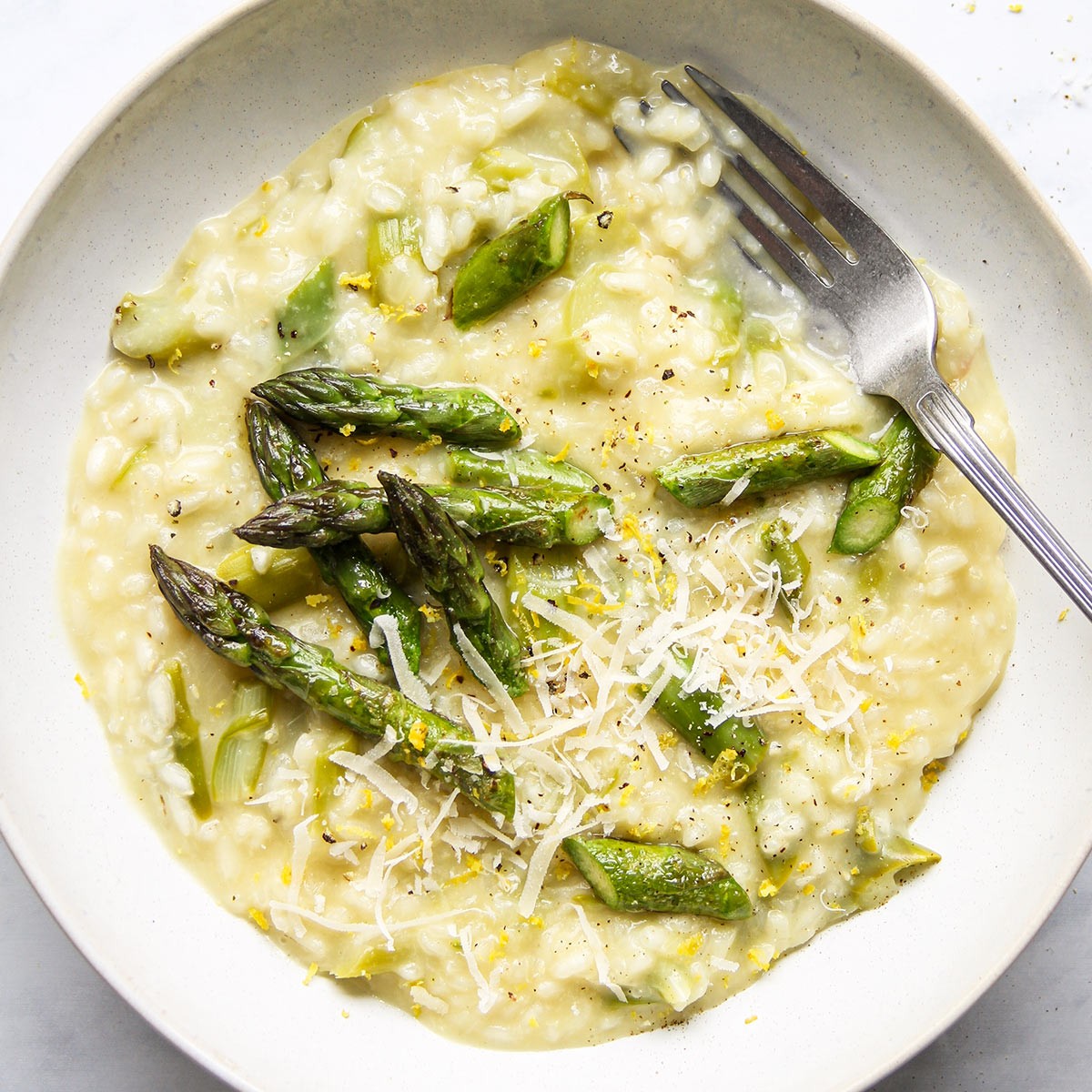 A creamy asparagus risotto with vibrant green asparagus spears and a sprinkle of red chili flakes.