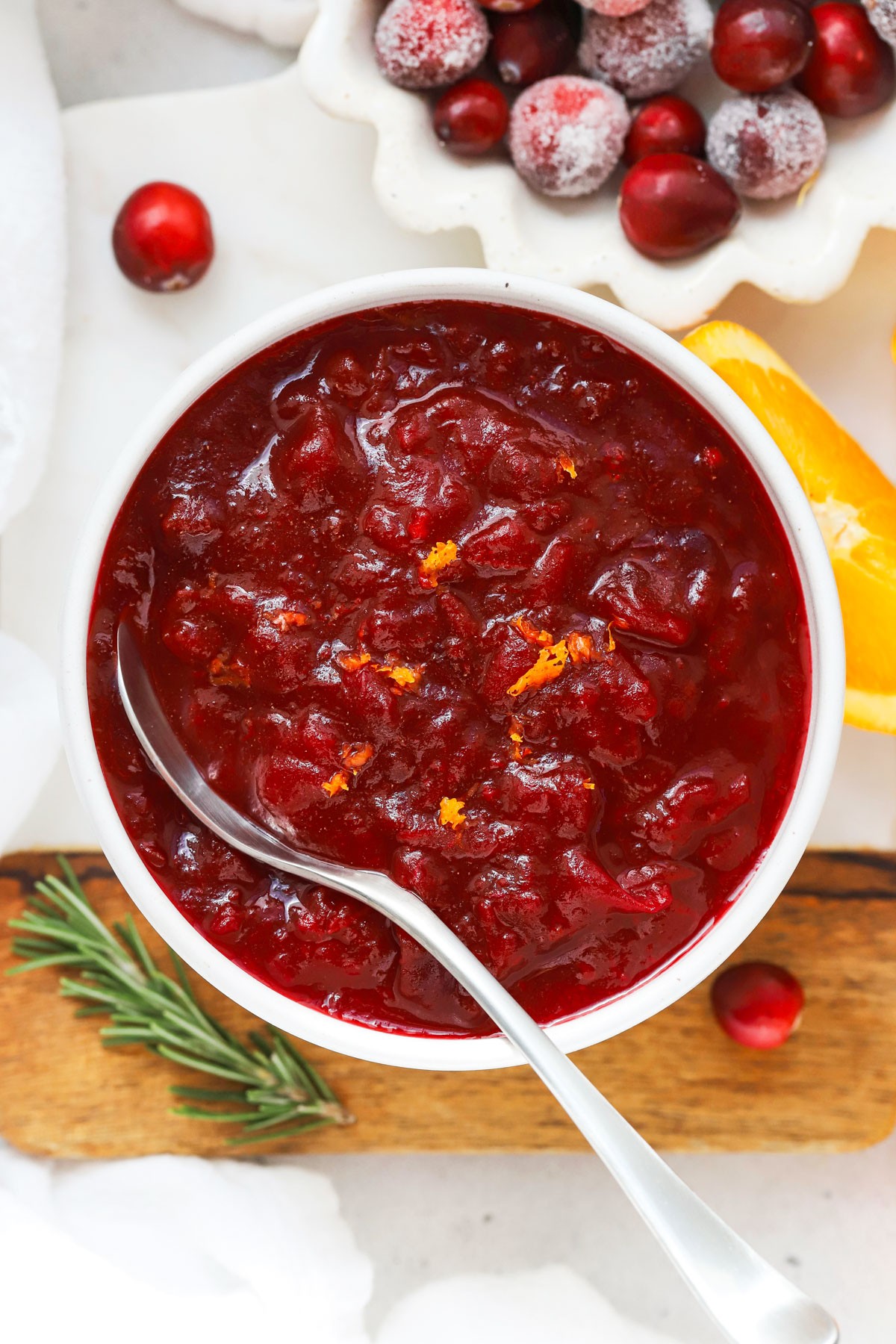 vibrant homemade cranberry sauce with honey drizzle in a ceramic bowl, garnished with orange zest and fresh cranberries