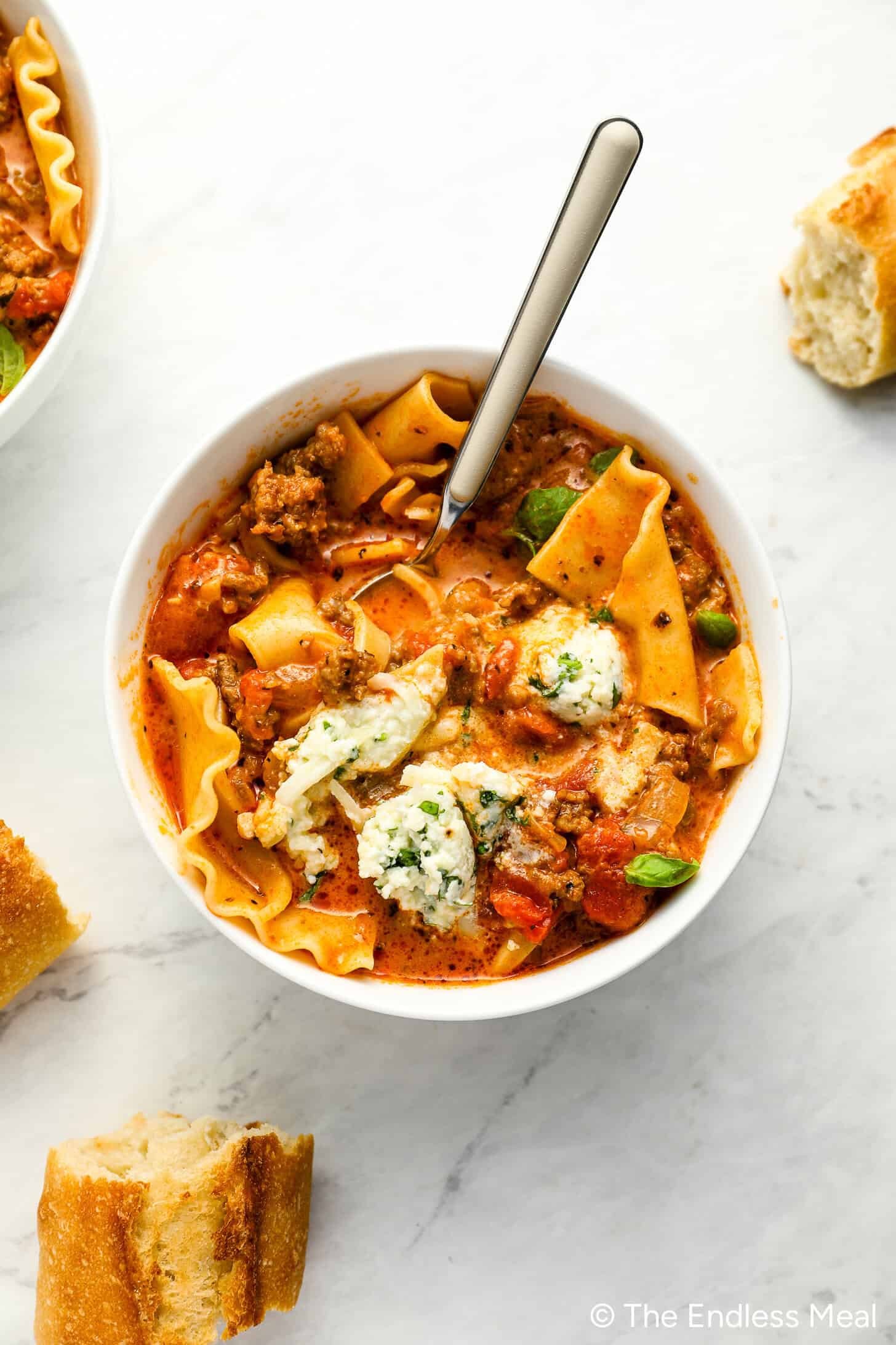 bowl of creamy lasagna soup topped with fresh basil and ricotta cheese