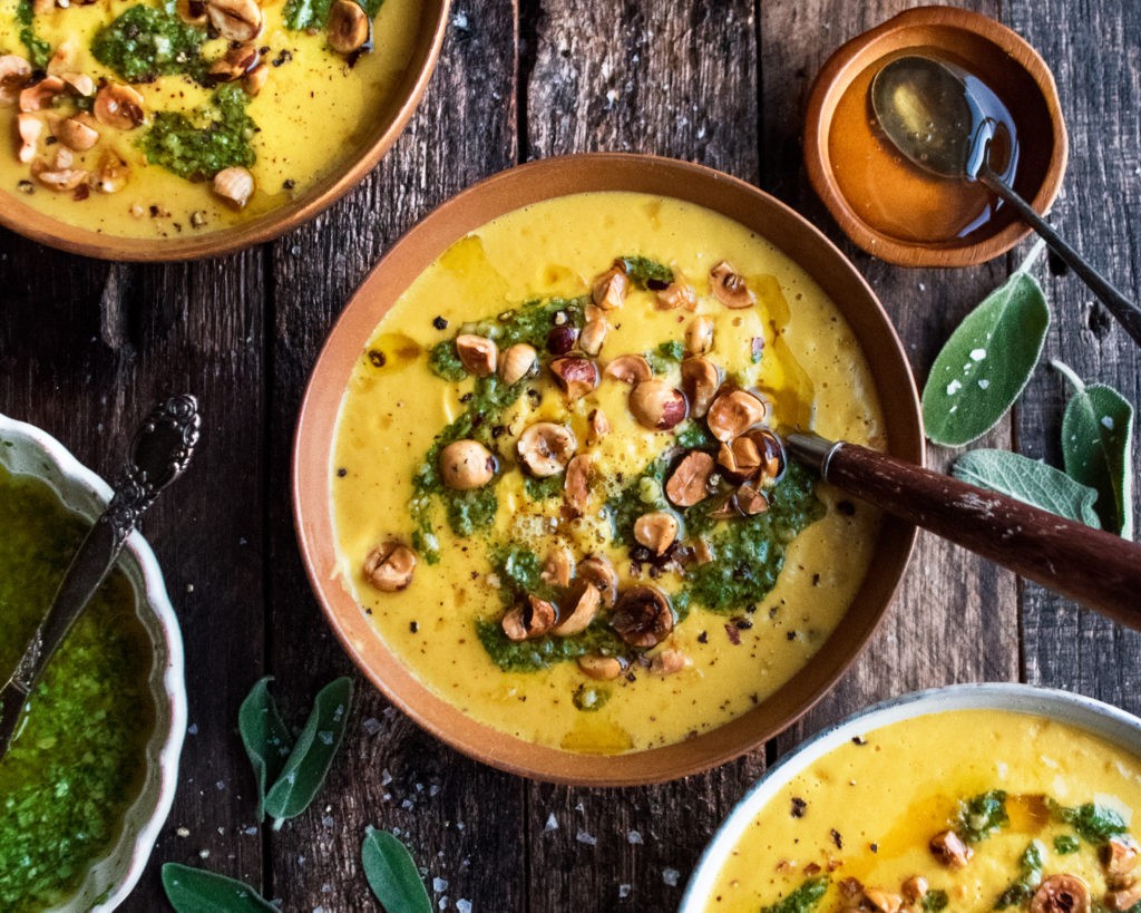 creamy roasted pumpkin sage soup in a rustic bowl, garnished with fresh sage leaves and croutons, cozy autumn setting