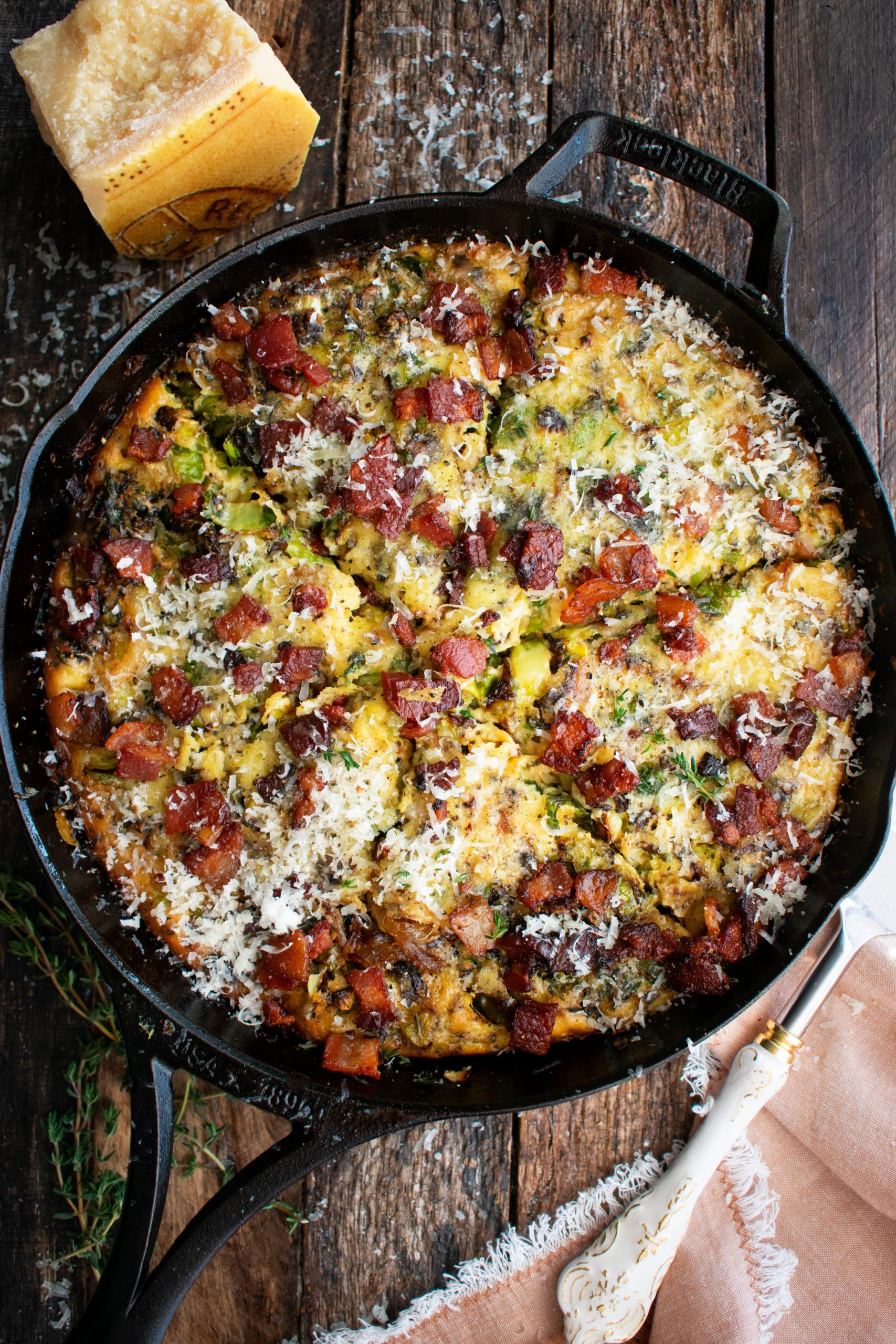 A golden-brown frittata with crispy bacon and caramelized onions, garnished with fresh herbs.