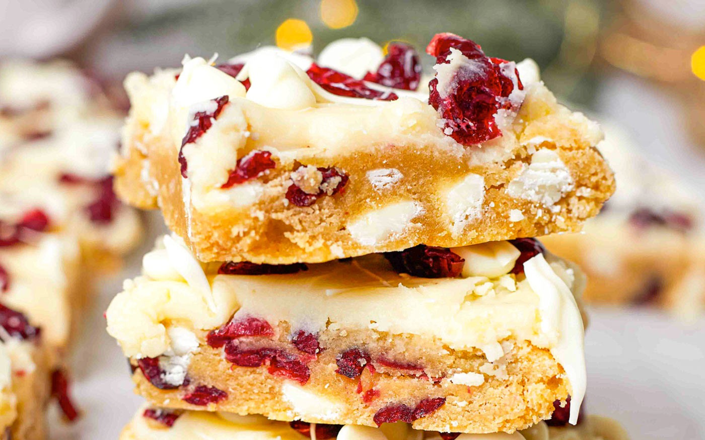 Festive cranberry bliss bars with white chocolate drizzle on a rustic wooden board, holiday background