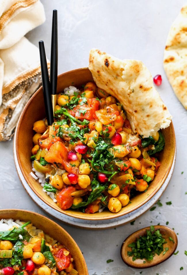 close up of curried chickpea salad in a bowl with naan bread