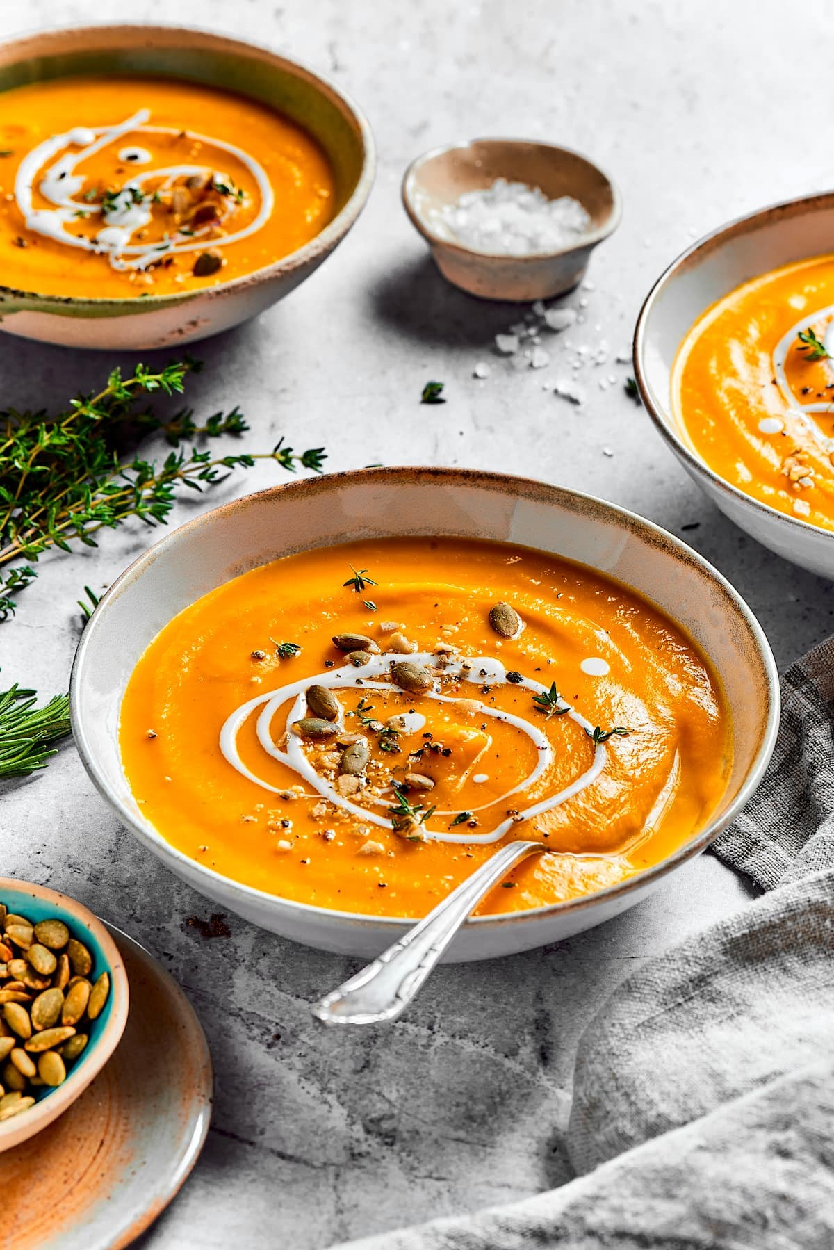 Bowl of butternut squash soup with toppings, warm lighting
