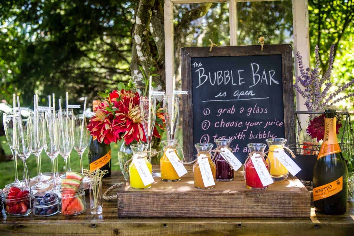 a beautifully arranged mimosa bar with various fruits, juices, and sparkling wines