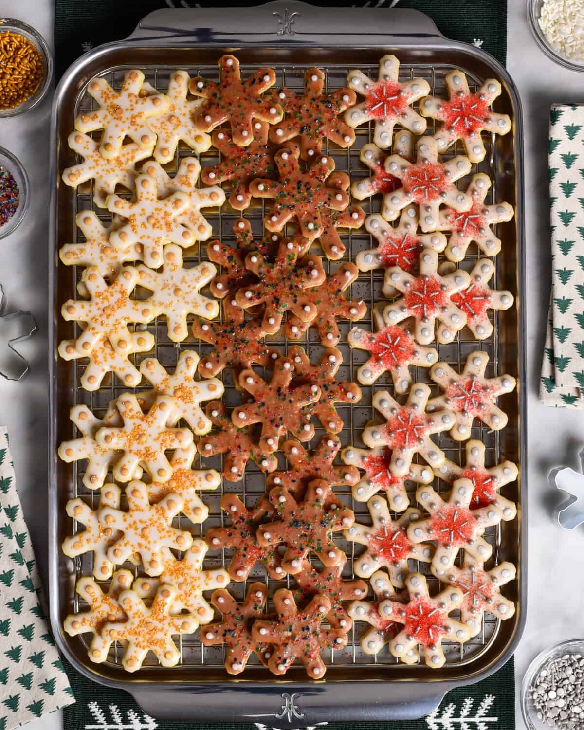 beautifully decorated glistening snowflake sugar cookies on a rustic wooden holiday platter with fairy lights