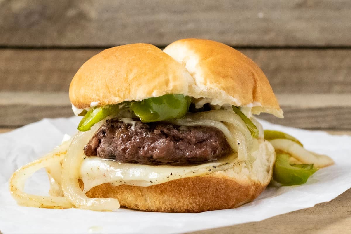 juicy philly cheesesteak burger with provolone drizzle close-up