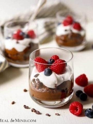 Close-up shot of a decadent avocado chocolate mousse topped with fresh berries in elegant glasses