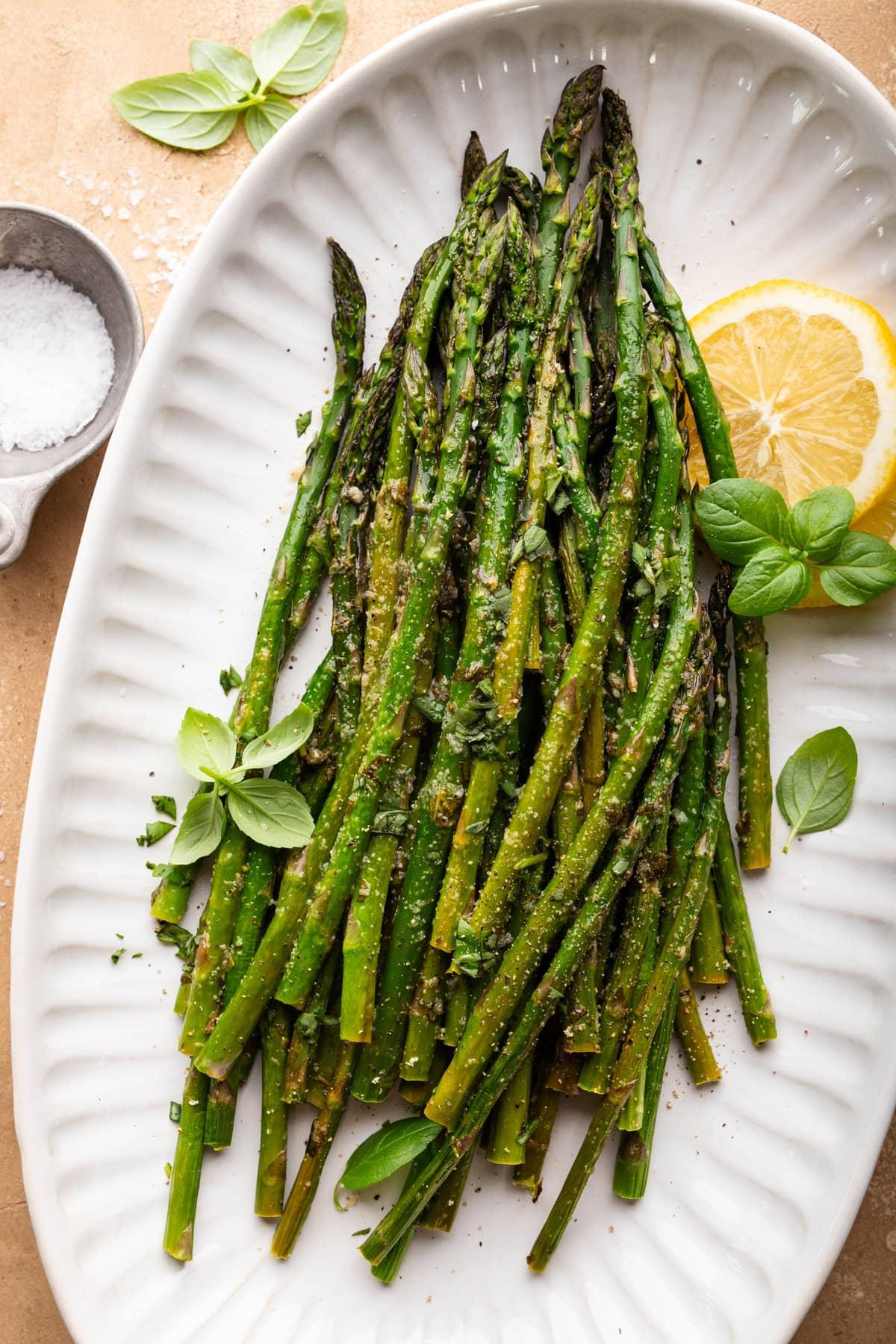 person preparing basil wrapped asparagus in the kitchen