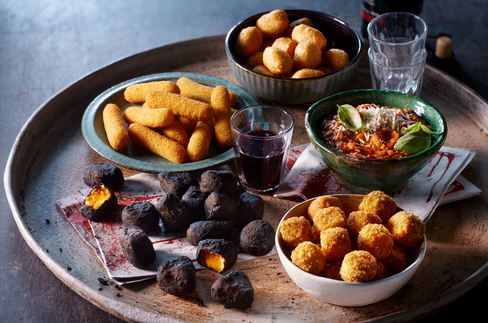 platter of spicy garlic parmesan bites party appetizers, guests reaching for food, bokeh background