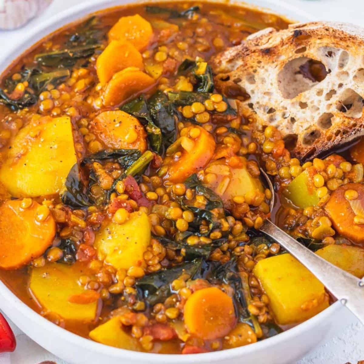 Cozy bowl of rich lentil vegetable stew with crusty bread, steam rising, natural light