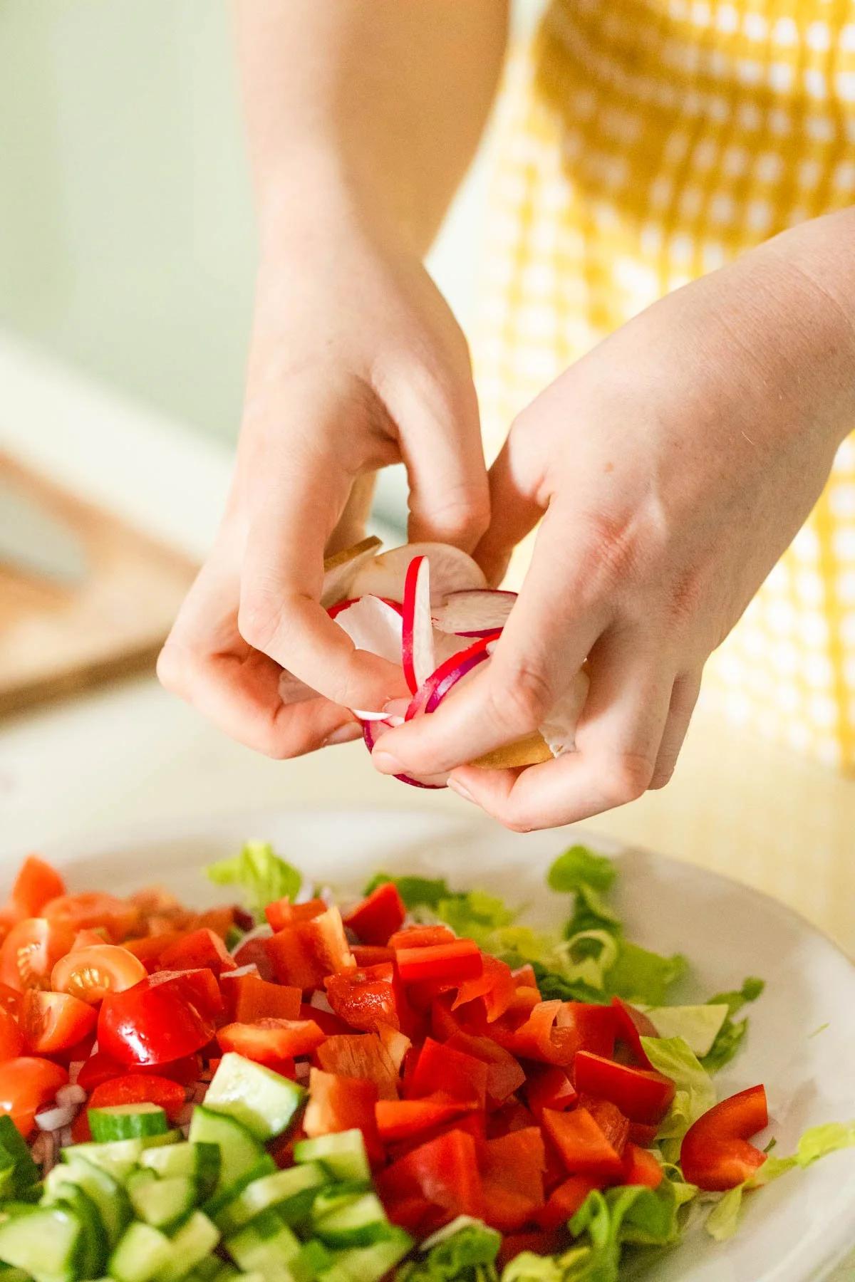 A person tossing a fattoush salad in a large bowl