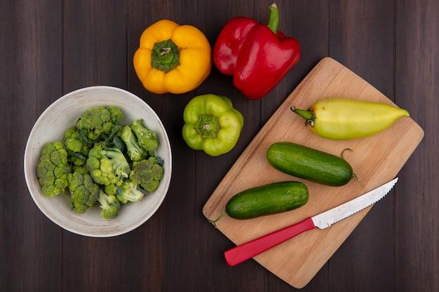 Overhead shot of colorful bell peppers being prepared with fresh mushrooms and herbs on a wooden cutting board