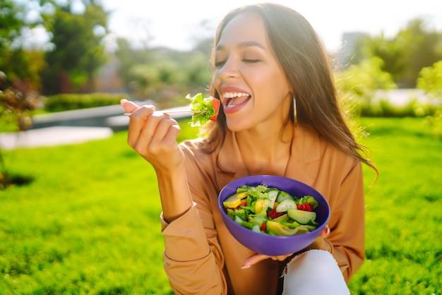 A person enjoying a bowl of Spicy Mango Fattoush salad outdoors on a sunny day.